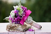Festlicher Blumenstrauss mit pinkfarbener Schleife und Perlenschmuck, auf Damen Abendtasche mit Pailletten