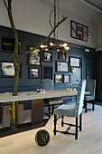 Custom wooden table with metal frame, upholstered vintage chairs, collection of pictures and basket ball hoop on wall