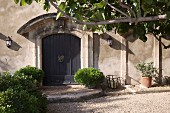 Potted shrubs flanking front door below curved porch of grand Mediterranean country house