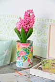 Pink hyacinth in tin decorated with floral pattern in shabby-chic ambiance with pastel green frieze on wall
