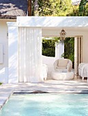 White wicker furniture in elegant summery lounge area next to pool
