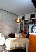 Extravagant round bed with fur blankets against white brick wall and shelves of records