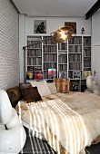 Extravagant round bed with fur blankets and retro standard lamp in front of white fitted shelves
