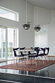 Dining area with modern chairs on ethnic rug below classic pendant lamps