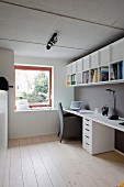 Schmales Arbeitszimmer mit hellem Dielenboden, weisser Schreibtisch mit Schubladencontainer, oberhalb Regal an grau getönter Wand