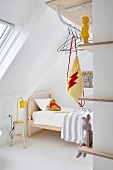 Wooden bed, clothes rail and narrow shelves in minimalist child's bedroom