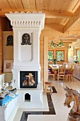 White ornate stove in living room of elegant wooden house with carved decorations