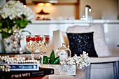Weißwein mit Himbeeren in Kristallgläsern in elegantem Wohnraum