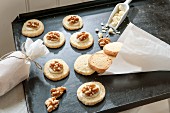 Christmas biscuits topped with walnuts on baking tray