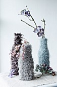 Dried flowers in vases in knitted and crocheted covers