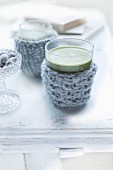 Glasses of green matcha tea in knitted glass cosies