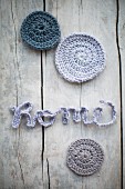 Crocheted cord arranged to spell 'Home' and round pastel castors on vintage wooden surface