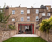 View from courtyard; traditional English brick house with open terrace doors and extension