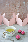 Spring herb tea in vintage cup, chocolates and paper Easter bunnies