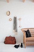 Cloakroom pegs made from round wooden discs, leather bag and wicker sofa