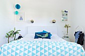 Double bed with blue and white bedspread and spherical wall lamps in retro-style bedroom