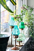 Candle lanterns with blue and green glass shades on windowsill