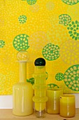 Yellow glass vases in front of yellow artworks with motif of circles