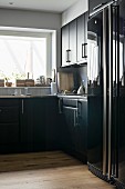 Black, L-shaped kitchen units and glossy fridge-freezer
