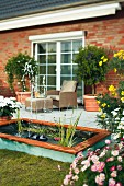 DIY pool with fountain and aquatic plants next to summery terrace