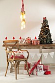 Pendant lamp above festively decorated rustic wooden ceiling, vintage chair and Christmas presents wrapped in red and white paper