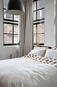 Bett mit Blick aus Sprossenfenstern auf Nachbarhaus
