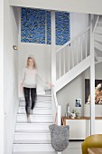 Woman walking down staircase into living room