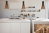 Weisser Küchenblock und Frühstückstheke mit Pendelleuchten in offener Küche