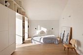 White fitted wardrobes in simple attic bedroom with parquet floor