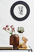 Wooden vase and toadstool ornament on side table below picture of elephant on wall