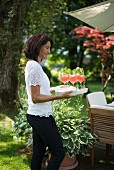 Woman serving refreshing trays on tray in garden