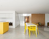 Minimalistischer Wohnraum mit Betonboden, Küche und Essbereich in Gelb & Weiß