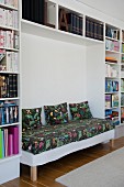 Bench with floral seat cushion and matching scatter cushions integrated in modern fitted shelving