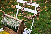 Wreath of acorns and wooden crate of heather on garden chair
