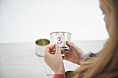 Girl sticking number onto tin can for DIY Advent calender