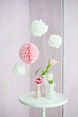 Pompoms and paper honeycomb ball above tulips in vases wrapped in cord