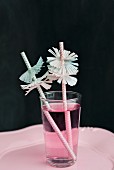 Drinking straws with paper collars and pink drink in glass