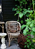 Vintage rattan chair and basket on terrace in garden against wooden wall