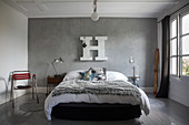 Fur blanket on bed below large white decorative letter on grey stucco lustro wall