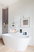 Free-standing bathtub below gallery of pictures on wall