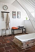 White wood-panelled walls and ceiling in rustic bathroom with brick surround around sunken bathtub