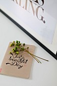 Sprig of berries on top of notebook with calligraphy motto on front