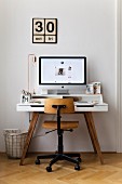 Computer on modern desk and vintage chair