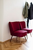 Red, retro easy chairs next to coat rack in hall