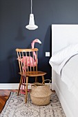 Flamingo behind Windsor chair used as bedside table against dark wall