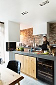 Woman and cat in modern kitchen with brick wall