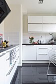 Wall-mounted cabinet and glossy black-tiled floor in white fitted kitchen