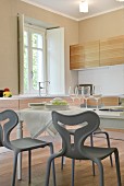 Set dining table and modern, grey plastic chairs in kitchen of renovated country house