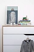 Modern white chest of drawers with children's books and framed picture