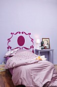 Bed headboard stencilled on wall in purple bedroom